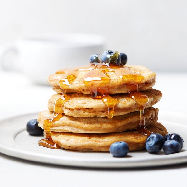 A stack of pancakes with Smucker's syrup on top.