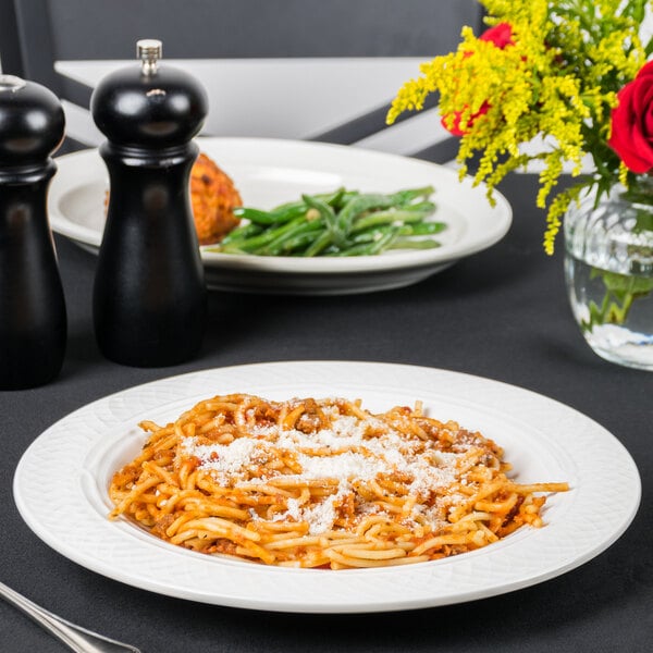 A plate of pasta with cheese and vegetables served in a Homer Laughlin bright white china pasta bowl.