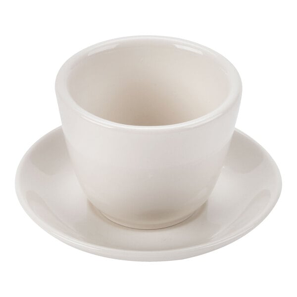 A small, ivory-colored ceramic cup placed on a matching saucer.