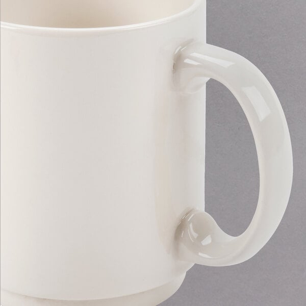 A close up of a Homer Laughlin ivory stackable china mug with a handle.