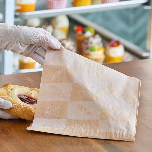 A natural kraft artisan print deli wrap or double open bag being used to hold a pastry.