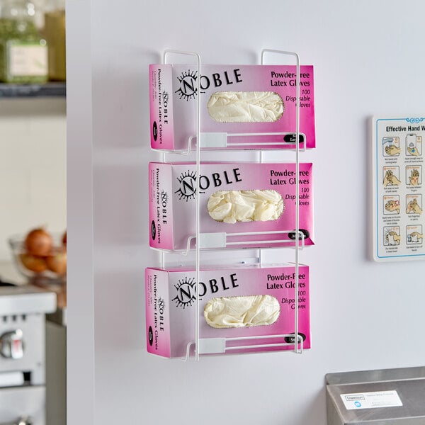 A three-tier wire wall mount dispenser holding boxes of disposable gloves.