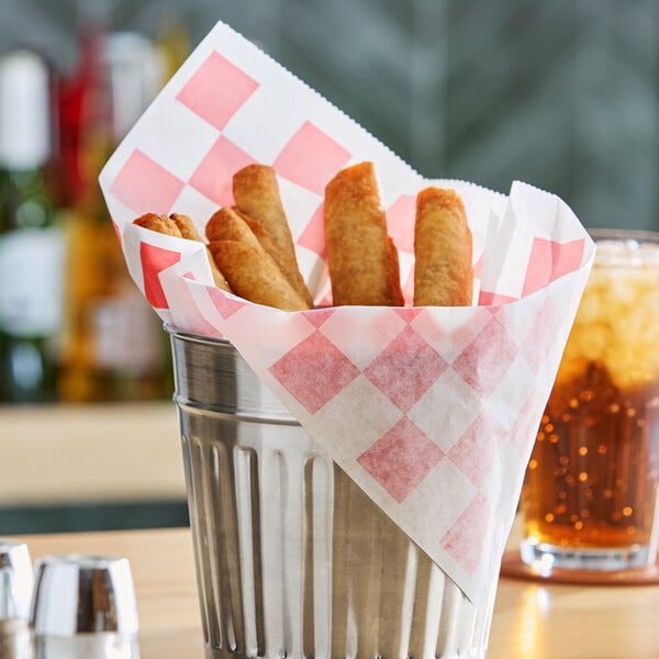 A metal basket lined with a red checkered deli wrap holding several fried food items.