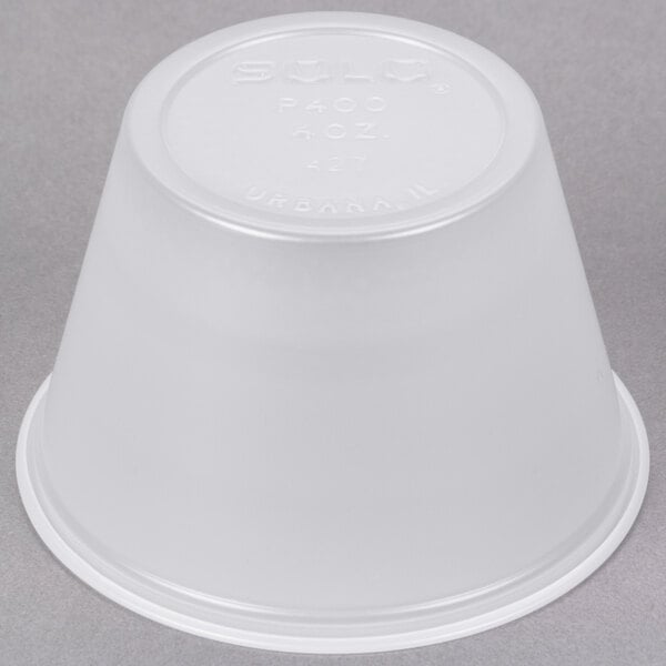 A translucent Solo polystyrene souffle cup on a gray surface.