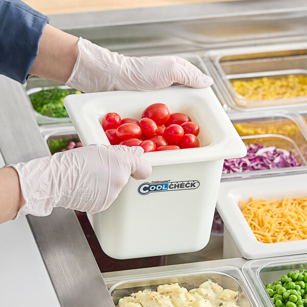 A person in gloves using a Carlisle white plastic food pan to serve cherry tomatoes in a salad bar.