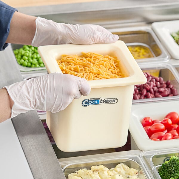 A person in gloves holding a Carlisle white container of food.