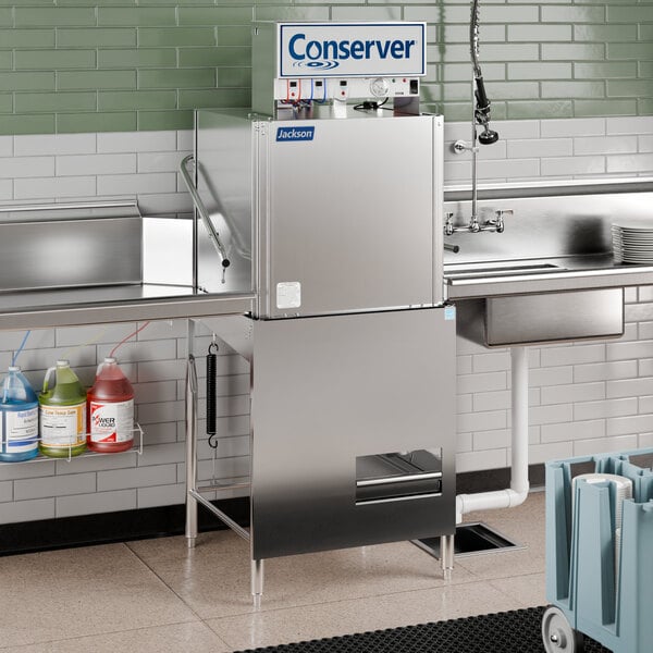 A Jackson Conserver XL-E low temp door type dish machine on a counter in a stainless steel commercial kitchen.