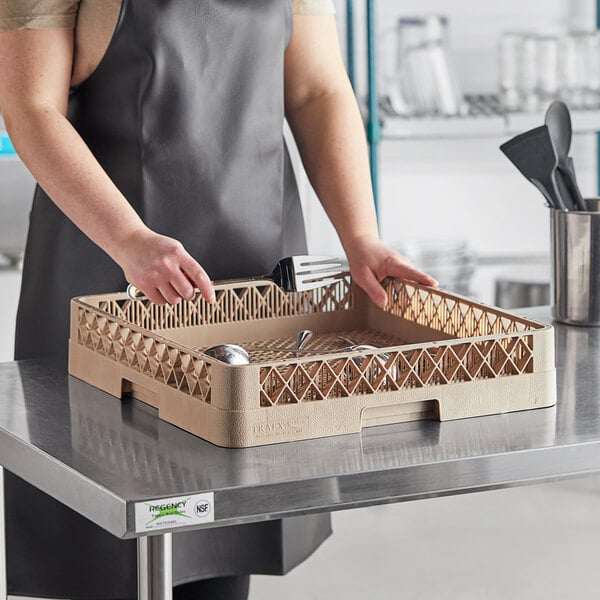 A woman in an apron holding a Vollrath Traex flatware rack full of spoons and forks.