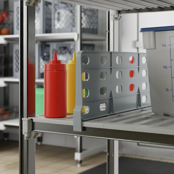 A grey Cambro shelf divider on a shelf with condiment containers.