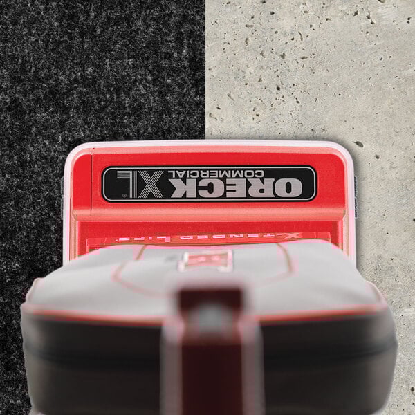 A red and grey Oreck upright vacuum cleaner with a white logo.