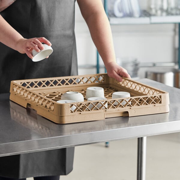A woman holding a white bowl in a Vollrath dish rack on a counter.