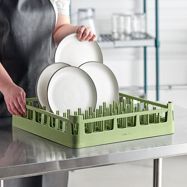 A person using a Vollrath Signature light green full-size extended plate rack to hold plates.