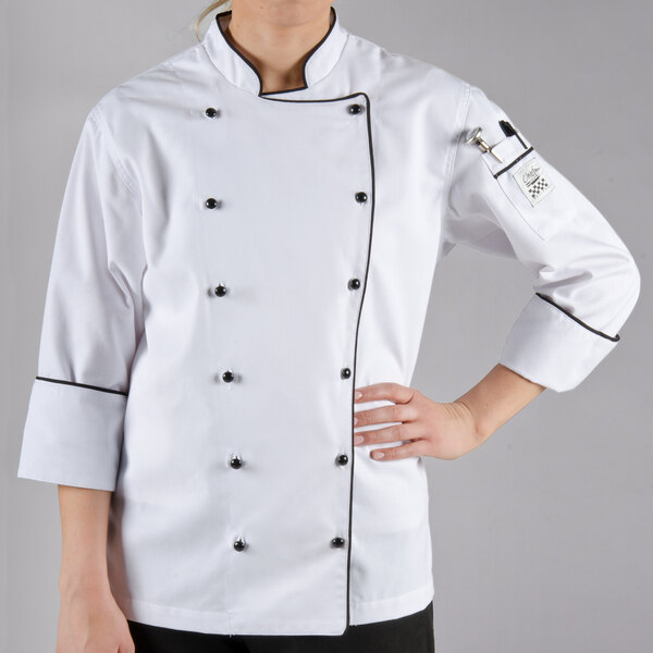 A woman wearing a white Chef Revival long sleeve coat with black piping.