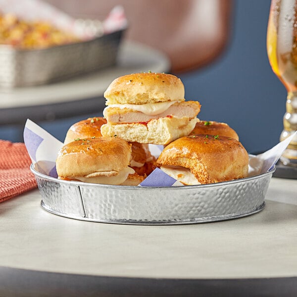 A Tablecraft galvanized steel diner platter holding sandwiches on a table.