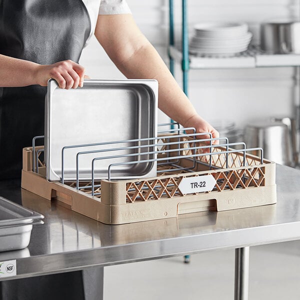 A woman using a Vollrath Traex open end steam table pan rack on a counter.