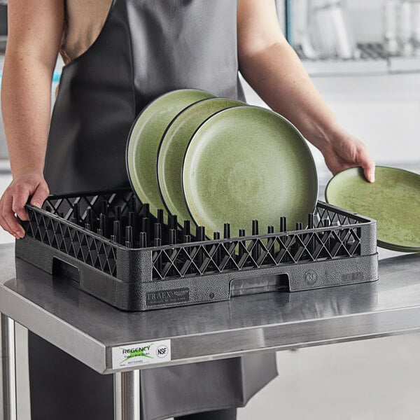 A woman holding plates in a Vollrath TR3 dish rack.