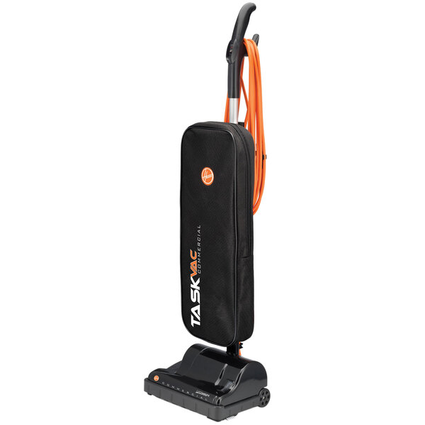 A black and orange Hoover Task Vac commercial bagged vacuum cleaner with a handle.