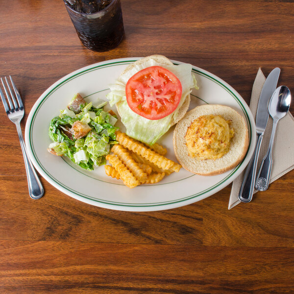 A Homer Laughlin green banded oval platter with a sandwich, fries, and a drink on a table.