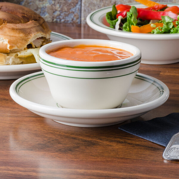 A bowl of soup and a sandwich on plates.