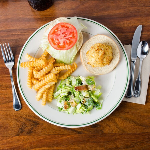A plate of food with a sandwich, fries, a tomato slice on the sandwich, and a knife and fork on the table.