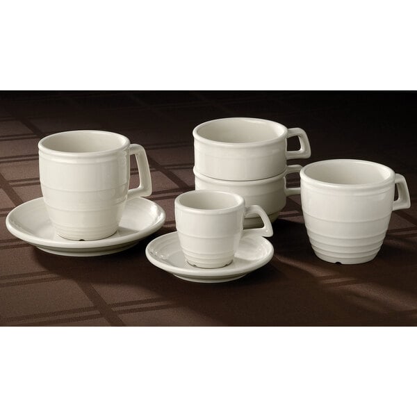 A group of Homer Laughlin ivory embossed saucers with white cups on saucers.