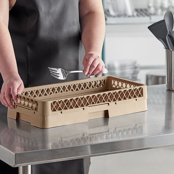 A woman holding a fork and spoon in a beige dish rack.