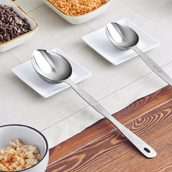 An American Metalcraft stainless steel portioned server spoon on a table with bowls of oatmeal and shredded carrots.