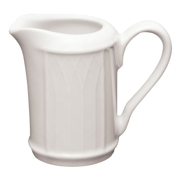 A small, ivory-colored ceramic creamer with a handle and spout, featuring a subtle embossed pattern.