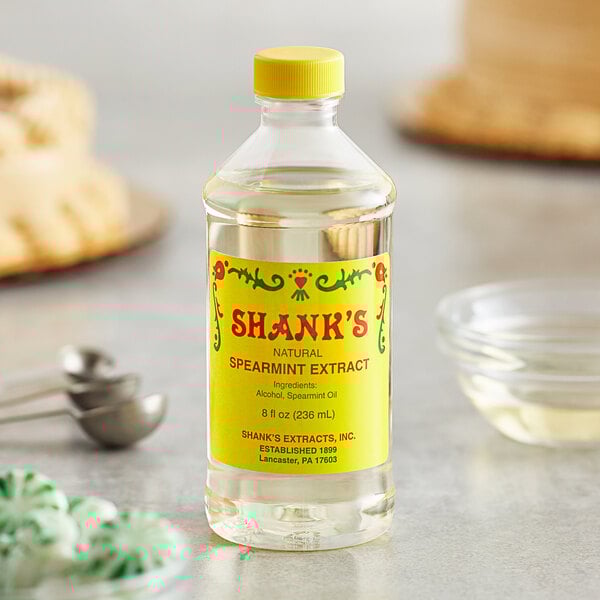 A close-up of a bottle of Shank's Pure Spearmint Extract on a table.