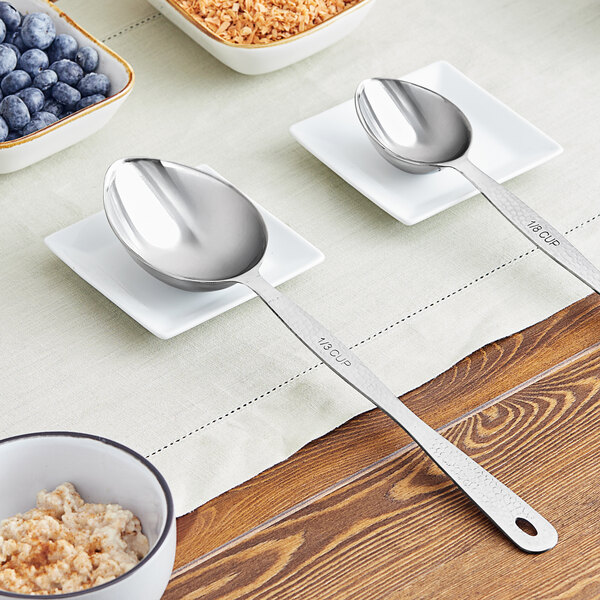 An American Metalcraft stainless steel hammered spoon on a table with bowls of oatmeal and blueberries.