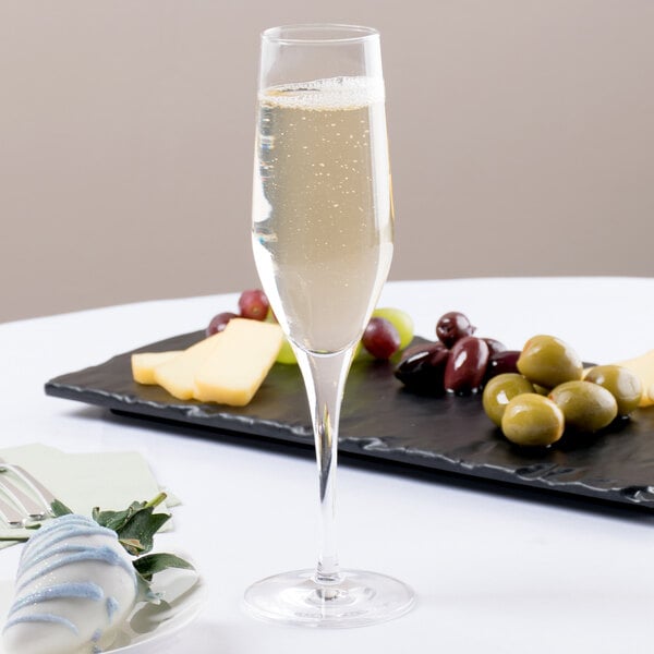 A Stolzle Exquisit flute glass of champagne next to a plate of fruit.