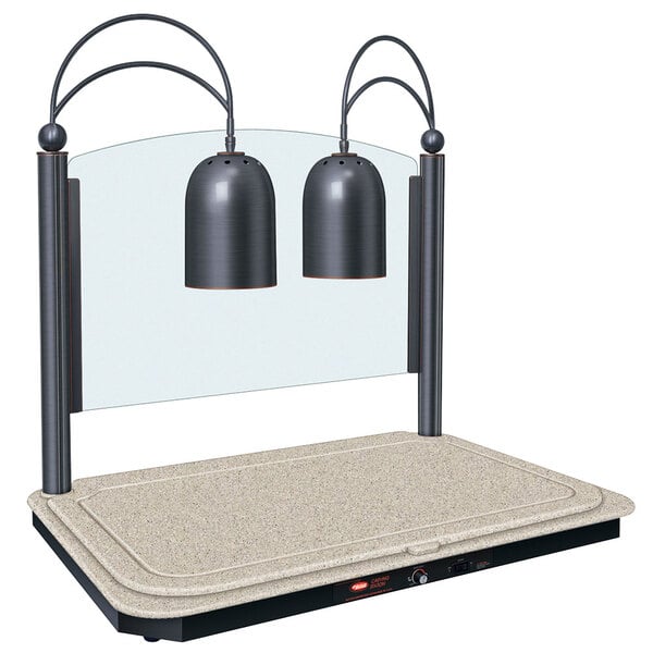 A Hatco carving station with Bermuda sand-colored base and antique bronze trim on a counter with two lamps.