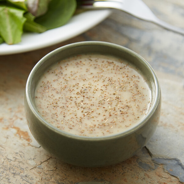 A bowl of soup with celery seeds next to a plate of salad.