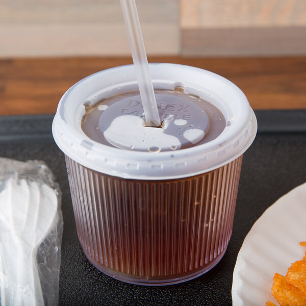 A translucent plastic Dinex lid with a straw slot on a Dinex Crystalon tumbler.