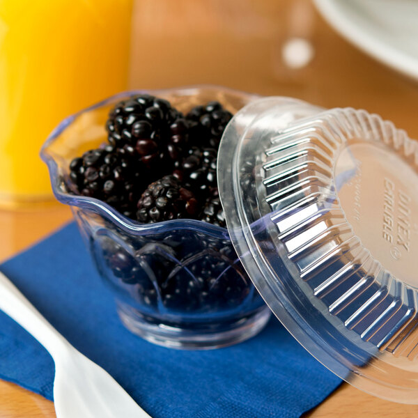 A clear plastic cup filled with blackberries.
