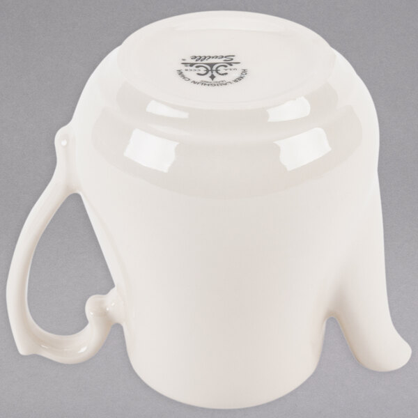 An ivory china beverage server with a lid and a handle.