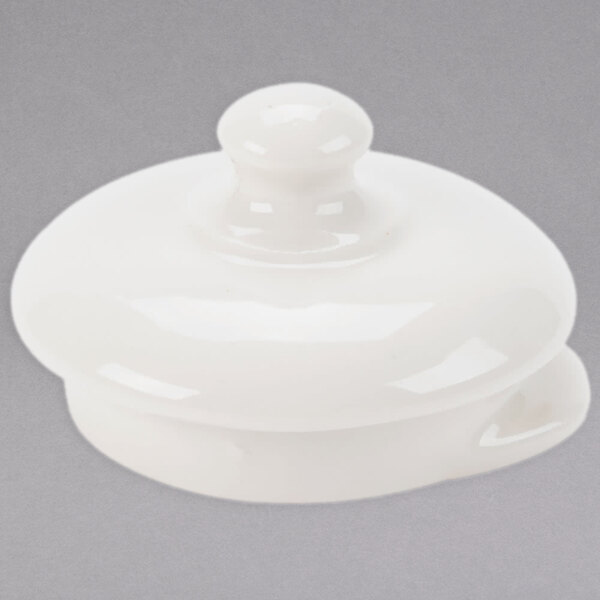 A white ceramic lid with a small knob on top over a white round object.