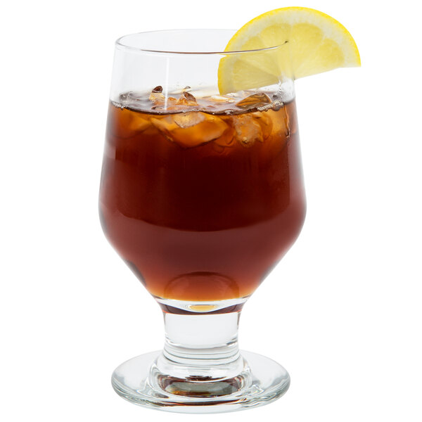 A Libbey footed goblet with a drink and a lemon slice.