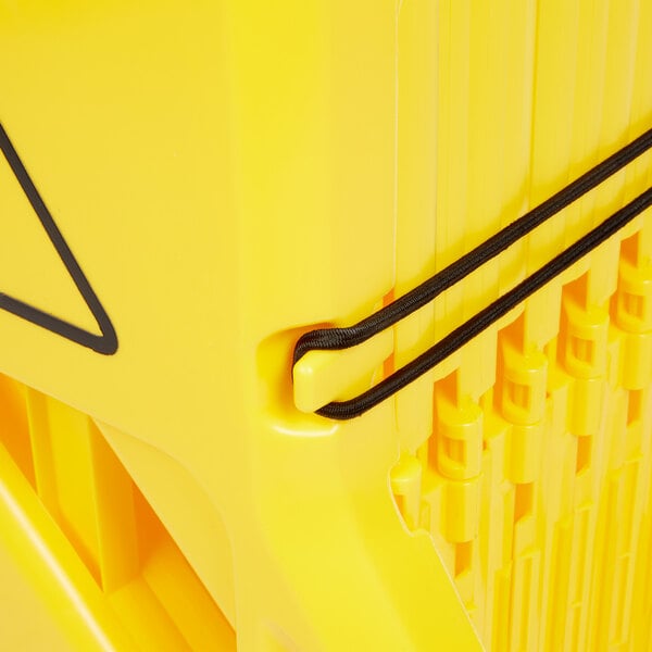 A close up of a stack of yellow Rubbermaid portable safety barriers.