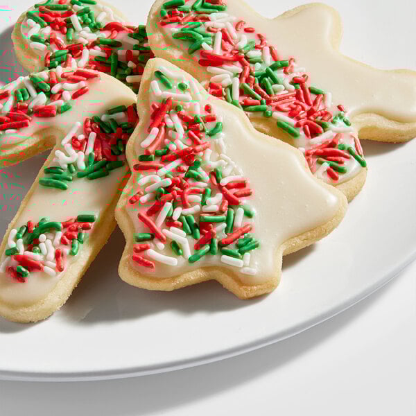A plate of Christmas-themed sugar cookies decorated with white icing and red, green, and white sprinkles.