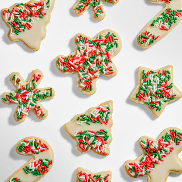 An assortment of Christmas-themed sugar cookies decorated with white icing and red, green, and white sprinkles.