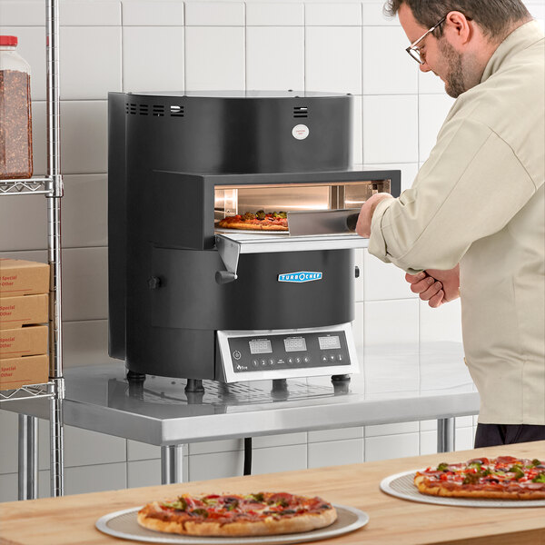 A man putting a pizza into a TurboChef Fire electric countertop pizza oven.