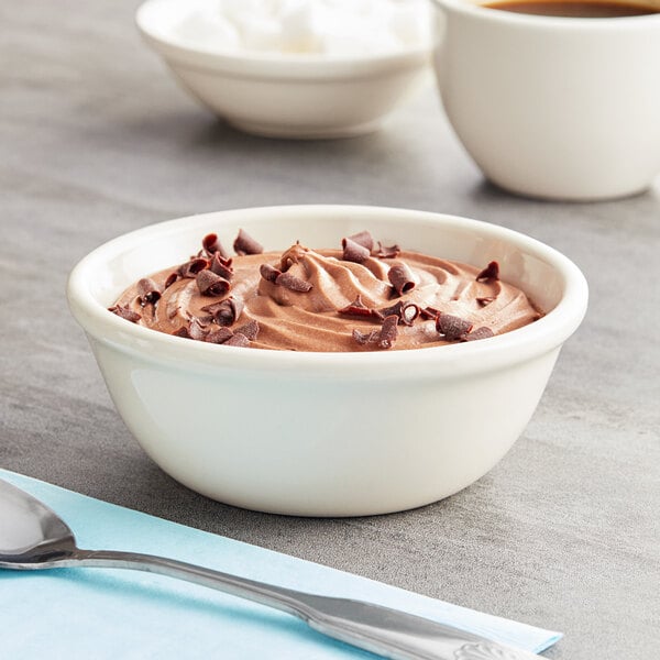 An Acopa ivory stoneware nappie bowl filled with chocolate pudding next to a cup of coffee.