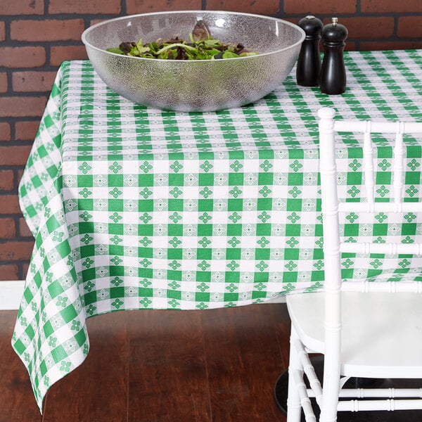 A green and white checkered vinyl table cover on a table with a bowl of salad.