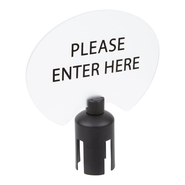 A black and white oval sign with the text 'PLEASE ENTER HERE' mounted on a black base.