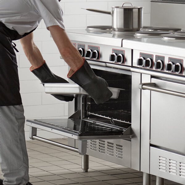 A man in a chef's outfit using a Garland electric range oven to cook food.