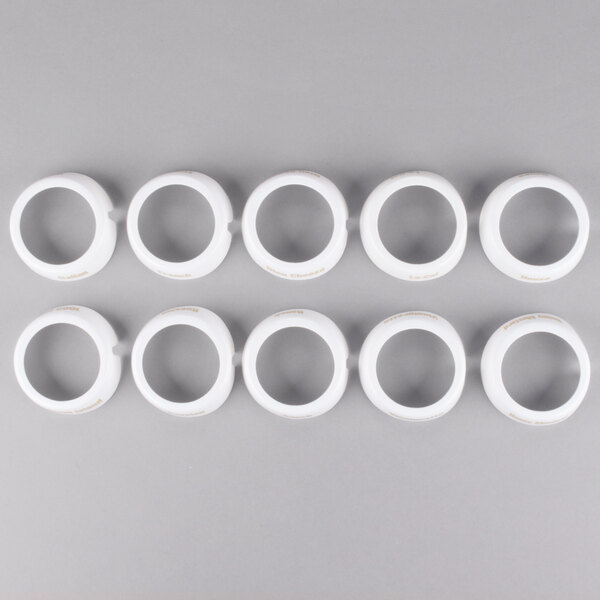 A row of white Tablecraft salad dressing dispenser rings with beige lettering on a gray surface.