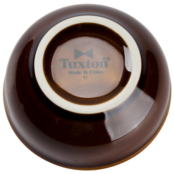 A brown Tuxton China sauce dish with a white logo.
