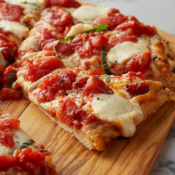 A slice of pizza with Furmano's tomato strips and cheese on a wood surface.