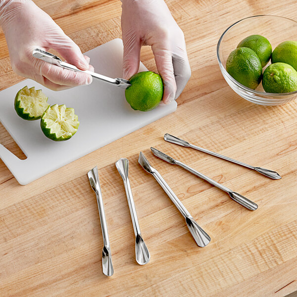 A person in gloves using a Town stainless steel garnishing tool to cut a lime.